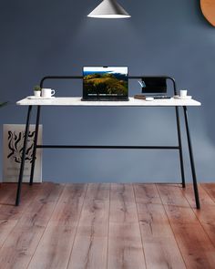 a laptop computer sitting on top of a white desk next to a plant and lamp