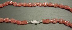 "With a total of approximately 228.00 carats of Genuine Earth-Mined Art Deco Shaped Interlocking Natural Watermelon / Coral Colored Rhodochrosite Gemstone beads with a Hand Engraved Platinum clasp Stamped: PT900 Necklace measuring approximately 16.25\" in length Weighing 45.7 grams Additional photos/details upon request. *Sale of necklace includes an appraisal certificate for your insurance purposes. All pieces shipped insured via USPS Priority Mail requiring signature upon delivery. Specialty g Luxury Oval Gemstone Beads Jewelry, Elegant Round Sunstone Jewelry, Elegant Sunstone Jewelry, Round Shape, Sunstone Jewelry With Round Natural Stones, Sunstone Gemstone Jewelry For Jewelry Making, Sunstone Gemstone For Jewelry Making, Elegant Sunstone Jewelry With Natural Stones, Round Sunstone Jewelry With Gemstone Beads, Art Deco Shapes