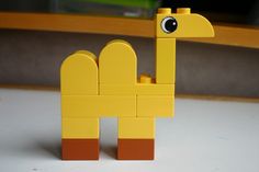 a yellow lego giraffe sitting on top of a table