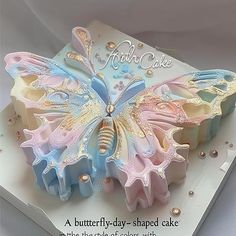 a butterfly shaped cake on top of a white box with gold and blue decorations around it