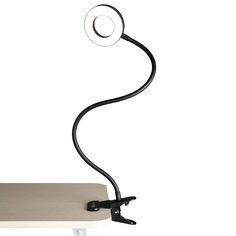 a desk lamp that is on top of a white surface and has a black cord attached to it