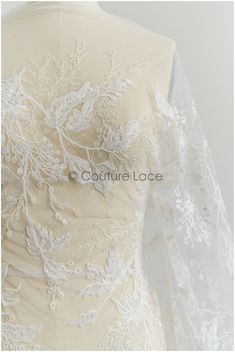 the back of a wedding dress with white lace on it