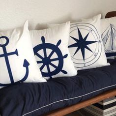 four pillows on a bench with an anchor, ship wheel and steering wheel in navy blue