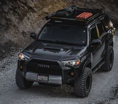 a black toyota 4runner is parked on the side of a mountain road in front of some rocks