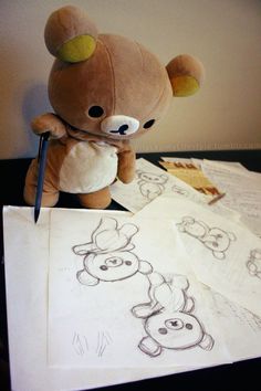 a teddy bear sitting next to some drawings