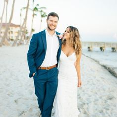 a bride and groom standing on the beach