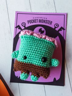 a crocheted green and brown object sitting on top of a card