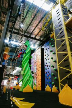 an indoor climbing wall with ropes and rocks