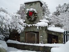 a stone fireplace covered in snow with a wreath on top