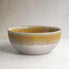 a white and yellow bowl sitting on top of a table next to a wall with no one in it