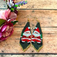 a pair of beaded earrings sitting on top of a wooden table next to flowers