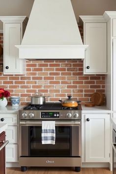 Modern kitchen with stainless steel stove, white cabinets, and brick backsplash. Dream Modern Farmhouse, Modern Farmhouse Kitchen Design, Earthy Elements, Large Kitchen Island, Mid Century Modern Bedroom, Farmhouse Kitchen Design, Modern Appliances