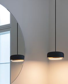 two circular lights hanging from the ceiling above a sink in a room with white walls