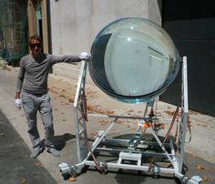 a man standing next to a metal object on the side of a road in front of a building