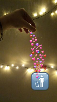 a hand is reaching for hearts floating from the ceiling with string lights behind it and an app icon on the screen