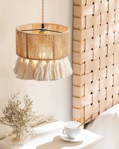 a table with a cup and saucer on it next to a lamp hanging from the ceiling