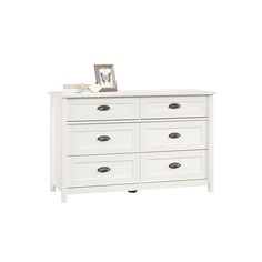 a white dresser with drawers and pictures on top