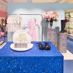 a blue table topped with lots of clothing and shoes next to vases filled with flowers