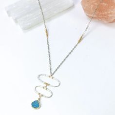 Shimmering blue druzy swings from the bottom of this unique hand forged pendant. Sterling silver ovals are connected carefully with gold filled wires, tapering down to showcase this stunning gemstone. This statement is accented with textured, silver chains, and tiny gold seed beads. From our Lagoon Collection. #rawgemstone #minimalstyle #uniquedesign •Sterling silver with 14k gold fill •Blue druzy with seed beads •Pendant Dimensions: about 1 x 1.75" •Length: 17" Unique Blue Hammered Jewelry, Forged Pendant, Beads Pendant, Silver Chains, Jewelry Lookbook, Raw Gemstones, Summer Jewelry, Beaded Pendant, Hand Forged