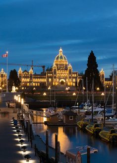 boats are docked in front of a large building with lights on it's sides