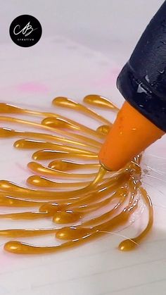 a person is using a pen to draw gold swirls on the surface of a sheet of paper