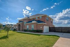 a large brick house sitting on top of a lush green field next to a fence