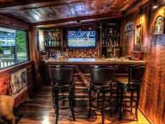 a home bar with stools and a television