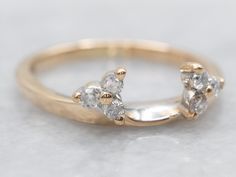 a gold ring with three diamond stones on the top and bottom, sitting on a white surface