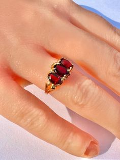 Gorgeous 10k yellow gold 3 stone Garnet gemstone ring! The lovely deep red gems weigh an estimated 2.28 ctw, they are oval faceted cut, and are prong set. There is a modern style setting. Unique piece of January's birthstone fine jewelry. ERA - Mid Century Era, Circa 1980's METAL / MATERIAL - 10k yellow gold, 3 garnet gemstones (estimated 2.28 ctw) MARKINGS / HISTORY - 10k SIZE / MEASUREMENTS - Size: 6 1/4, Rise Of Ring Off Of Finger: 5 mm, Shank: tapers to 2 mm, Gem: 7 x 5mm each, Weight: 3.2 g Oval Red Ruby Ring With Three Stones, Classic Red Three Stone Rings, Classic Red Three-stone Ring, Classic Three-stone Ruby Ring, Classic Ruby Ring Collectible, Classic Collectible Ruby Ring, Classic Yellow Gold Three Stone Ruby Ring, Classic Three Stone Yellow Gold Ruby Ring, Heirloom Three Stone Red Rings