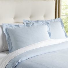 a bed with blue and white sheets and pillows