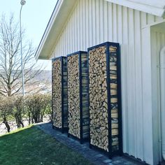 a row of firewood logs sitting next to a white building