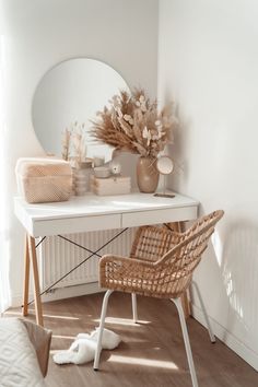 a white desk with a mirror, chair and vase on it in a room that has wood flooring