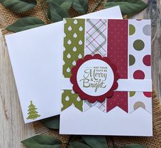 two christmas cards on top of each other next to some green leaves and greenery