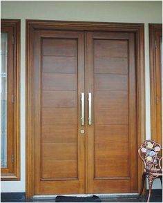 a chair sitting in front of a wooden door with sidelights on the outside wall