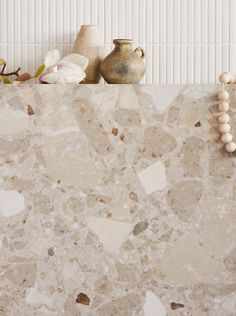 a marble counter top with some beads and vases on the shelf next to it