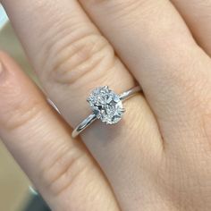 a woman's hand with a diamond ring on top of her finger and an engagement band