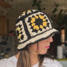 a woman wearing a black and white crocheted hat with yellow flowers on it