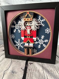 a wooden nutcracker with snowflakes on it's face in a shadow box