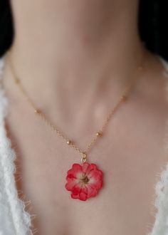 This stunning necklace features a beautiful, pressed red rose flower encased in a clear resin pendant.  The pendant is suspended from a luxurious chain, giving the necklace a touch of elegance and sophistication.  The vibrant red rose flower is a symbol of love and passion, making this necklace the perfect gift for a loved one or a special treat for yourself.  The delicate flower is carefully preserved, ensuring that their natural beauty will last for years to come. The gold-plated chain adds a Resin Jewelry Ideas Aesthetic, Preserved Flower Jewelry, Rose Red Flower Necklaces With Rose Design, Delicate Rose Flower Pendant Necklace, Delicate Flower-shaped Necklace With Rose Design, Delicate Flower Necklace With Rose Design, Delicate Necklace With Rose Flower Design, Rose Flower Charm Necklace For Valentine's Day, Rose Valentine's Day Necklace With Flower Charm