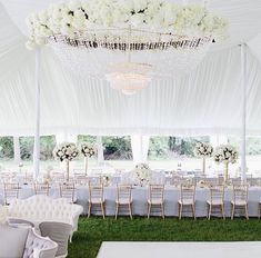 an outdoor wedding setup with white flowers and chandeliers