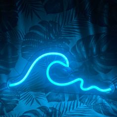 a neon sign that is on the side of a wall with palm leaves and plants