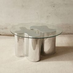 a glass and metal coffee table sitting on top of a floor