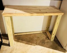 a wooden table sitting on top of a floor next to a white wall and door