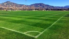 an empty soccer field with mountains in the background