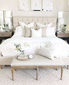 a white bed with pillows and blankets on top of it, next to two nightstands