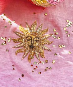 a pink cloth with gold sequins and a sun brooch