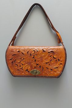 "Gorgeous vintage tooled leather purse. Floral design, scroll, textured, leather detail, edging, handmade, handcrafted. Adjustable leather strap with snaps for wrist or shoukder length drop approx. 8.5\" or 16\" Well kept bag with signs of age, use, wear, patina, marks, scratches, faint pen mark. Clean interior, zip compartments, brass tone hardware, patina. Stamped made in U.S.A. very faint marker's mark  interior as well. Lovely ol' bag." Vintage Embossed Leather Shoulder Bag, Vintage Leather Shoulder Bag With Embossed Details, Vintage Leather Embossed Shoulder Bag, Vintage Brown Embossed Shoulder Bag, Vintage Embossed Shoulder Bag For Daily Use, Vintage Leather Shoulder Bag With Engraved Details, Vintage Leather Shoulder Bag With Engraving, Vintage Engraved Leather Shoulder Bag, Vintage Engraved Shoulder Bag For Daily Use