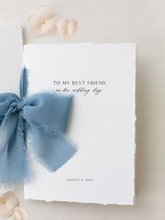 a wedding guest book with a blue ribbon tied around it and flowers on the side