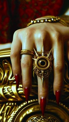 a woman's hand with red nails and gold rings