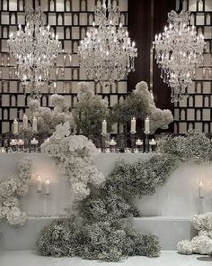 a room filled with lots of white flowers and chandeliers